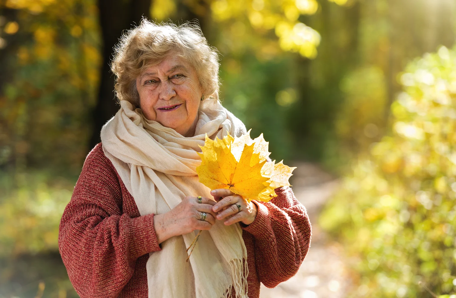 Elderly woman on a warm autumn day with leaves
