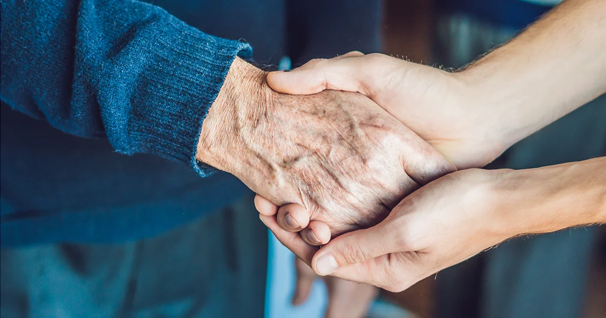close up of a worker holding an elderly patient's hand